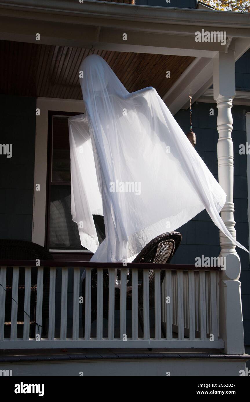 Halloween costume of a ghost hanging from a porch, swinging in the wind. Stock Photo