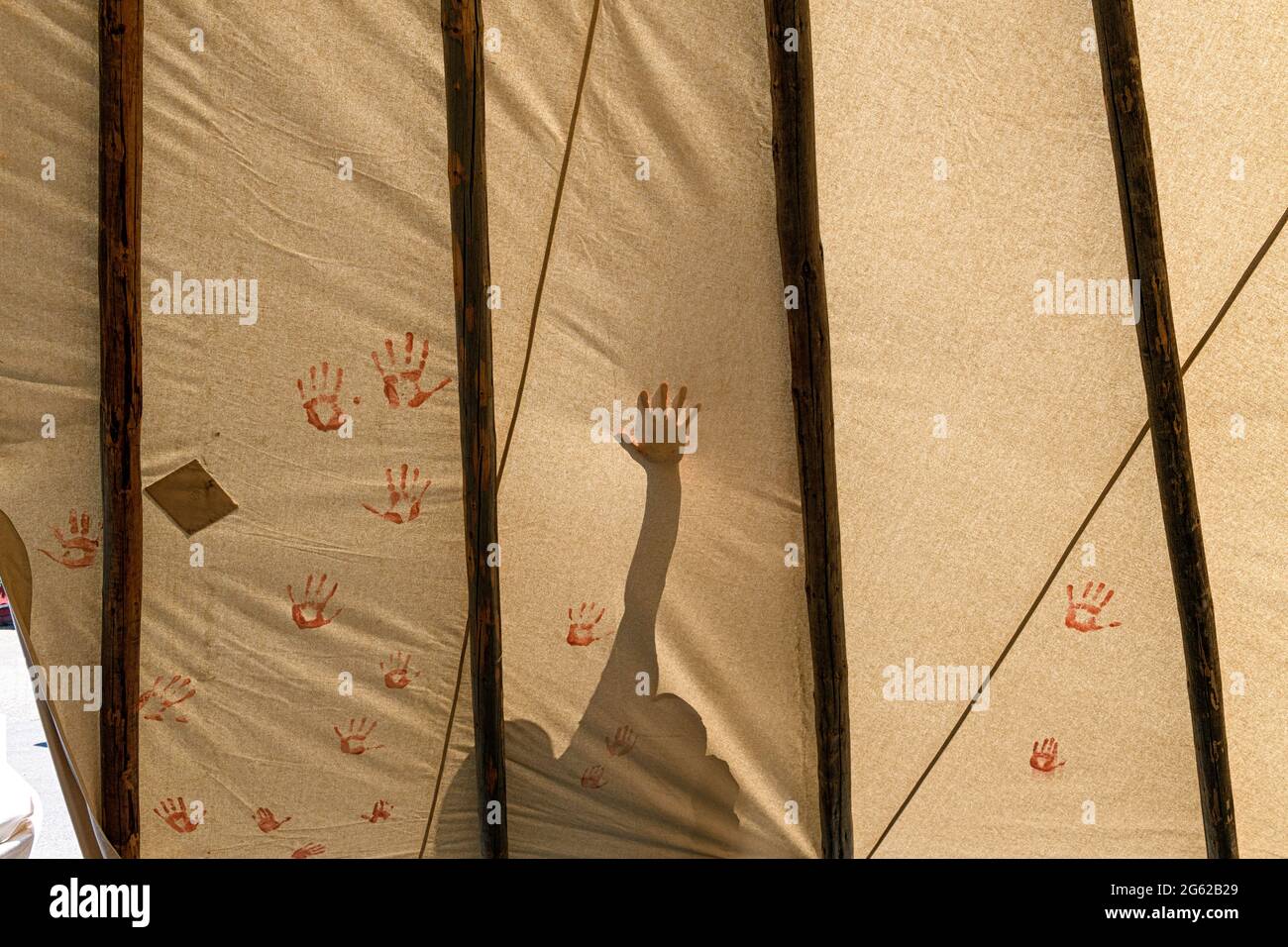 Indigenous  First Nations children placing painted hands on a teepee to commemorate  unmarked graves found on Canadian residential school property Stock Photo