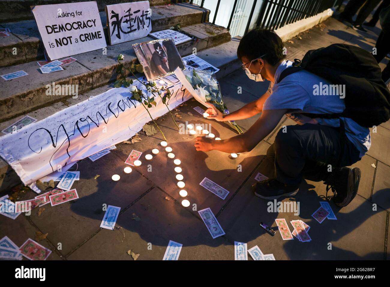 A protester lights candles in front of the Hong Kong Economic and Trade Office to mourn the death of a Hongkonger during the demonstration. Hongkongers held demonstrations in ten different cities in the UK to protest against the one year anniversary of the promulgation of the Hong Kong National Security Law and the Centennial anniversary of the Chinese Communist Party. In London, participants gathered outside the Chinese Embassy and marched to Chinatown where the main event took place. The crowds later moved to the Hong Kong Economic and Trade Office and set smoky flares outside as a symbolic Stock Photo