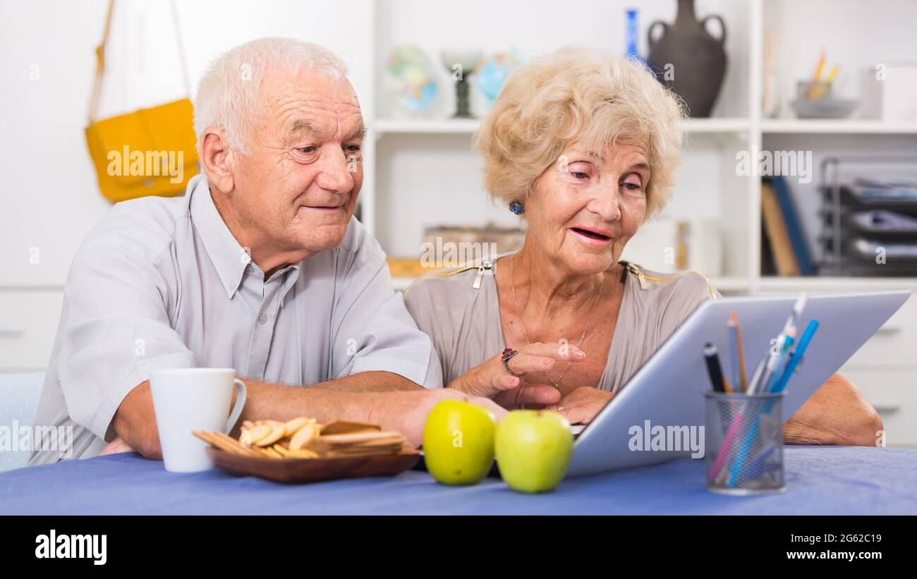 Cheerful mature spouses using laptop at home Stock Photo