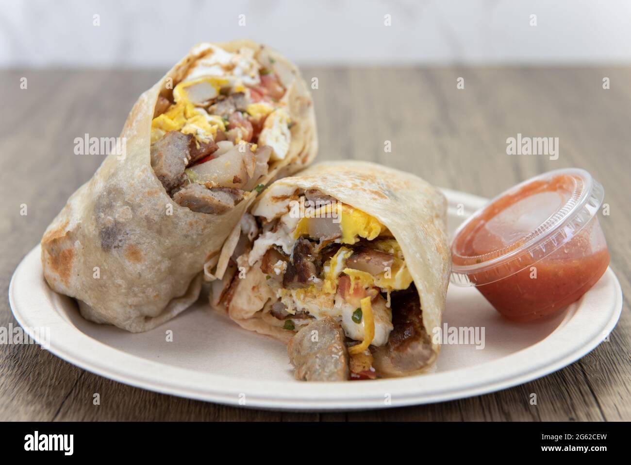 Breakfast burrito cut in half to show the loaded ingredients filling
