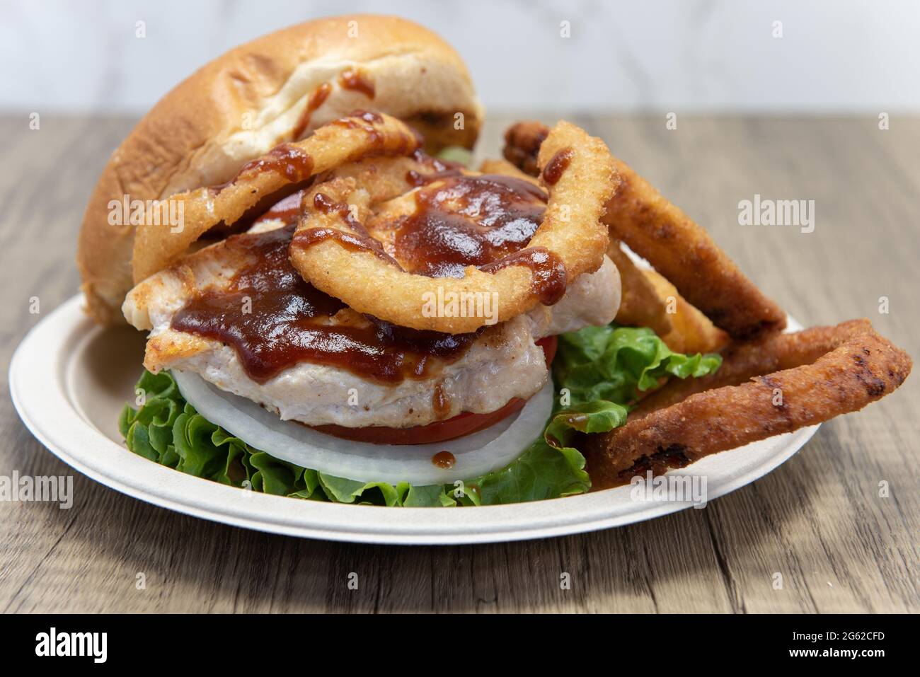 Barbeque chicken sandwich stacked tall in the toasted bun with huge