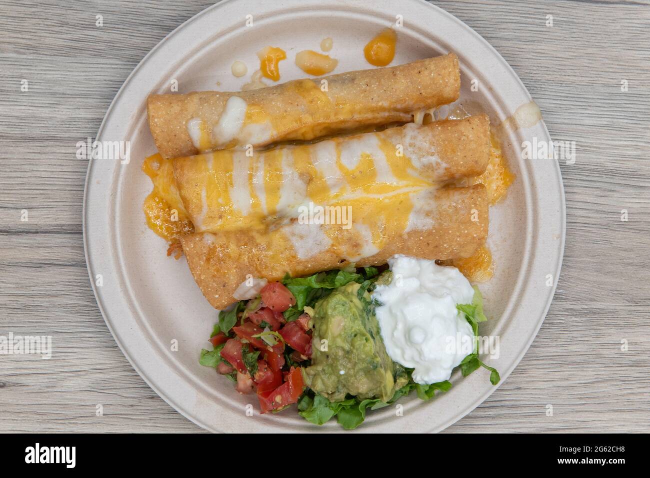 Overhead view of three crispy deep fried chicken taquitos covered with