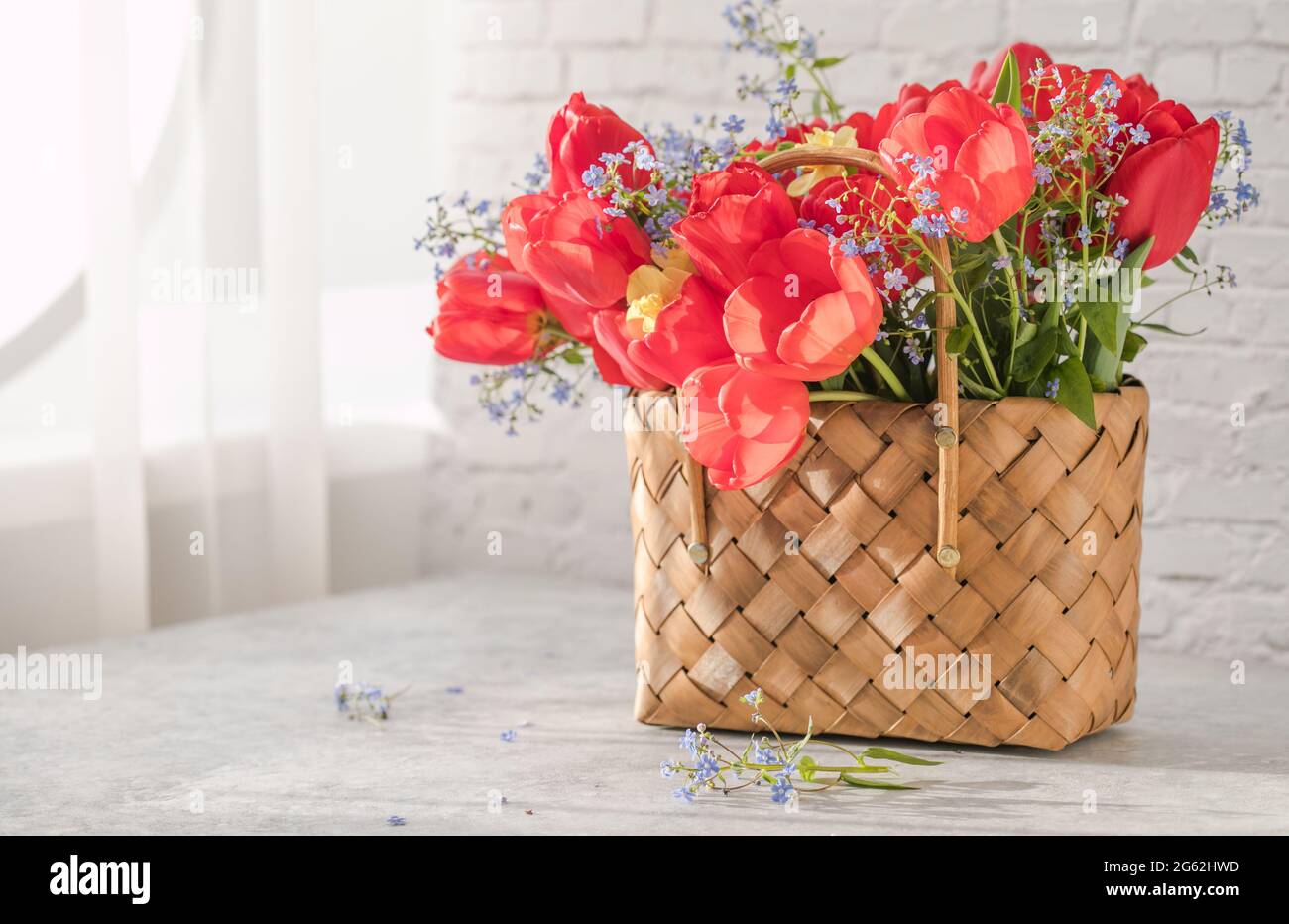 Summer or spring bouquet of daffodils and red tulips in a wicker basket ...