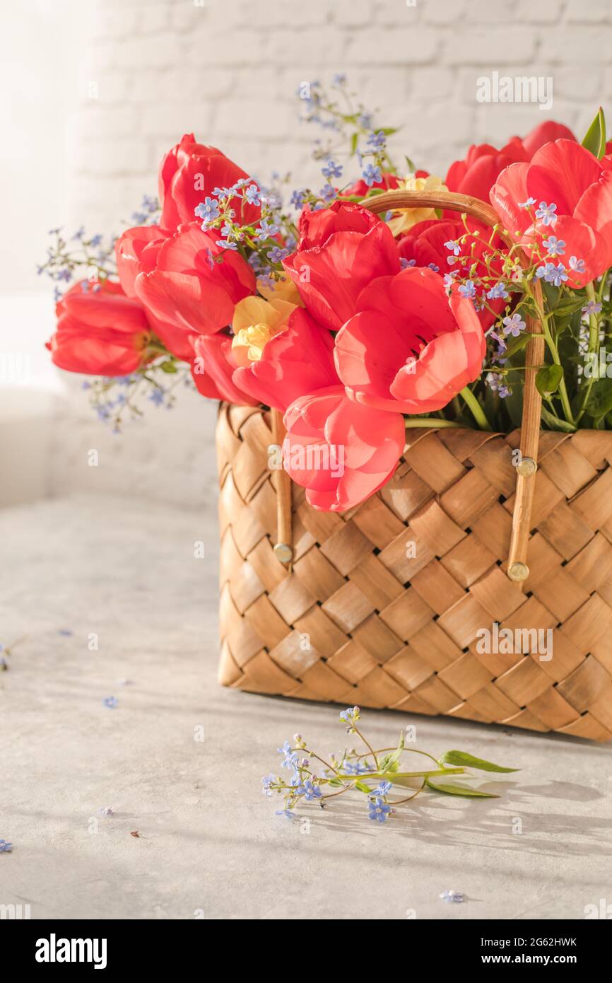 Summer or spring bouquet of daffodils and red tulips in a wicker basket ...