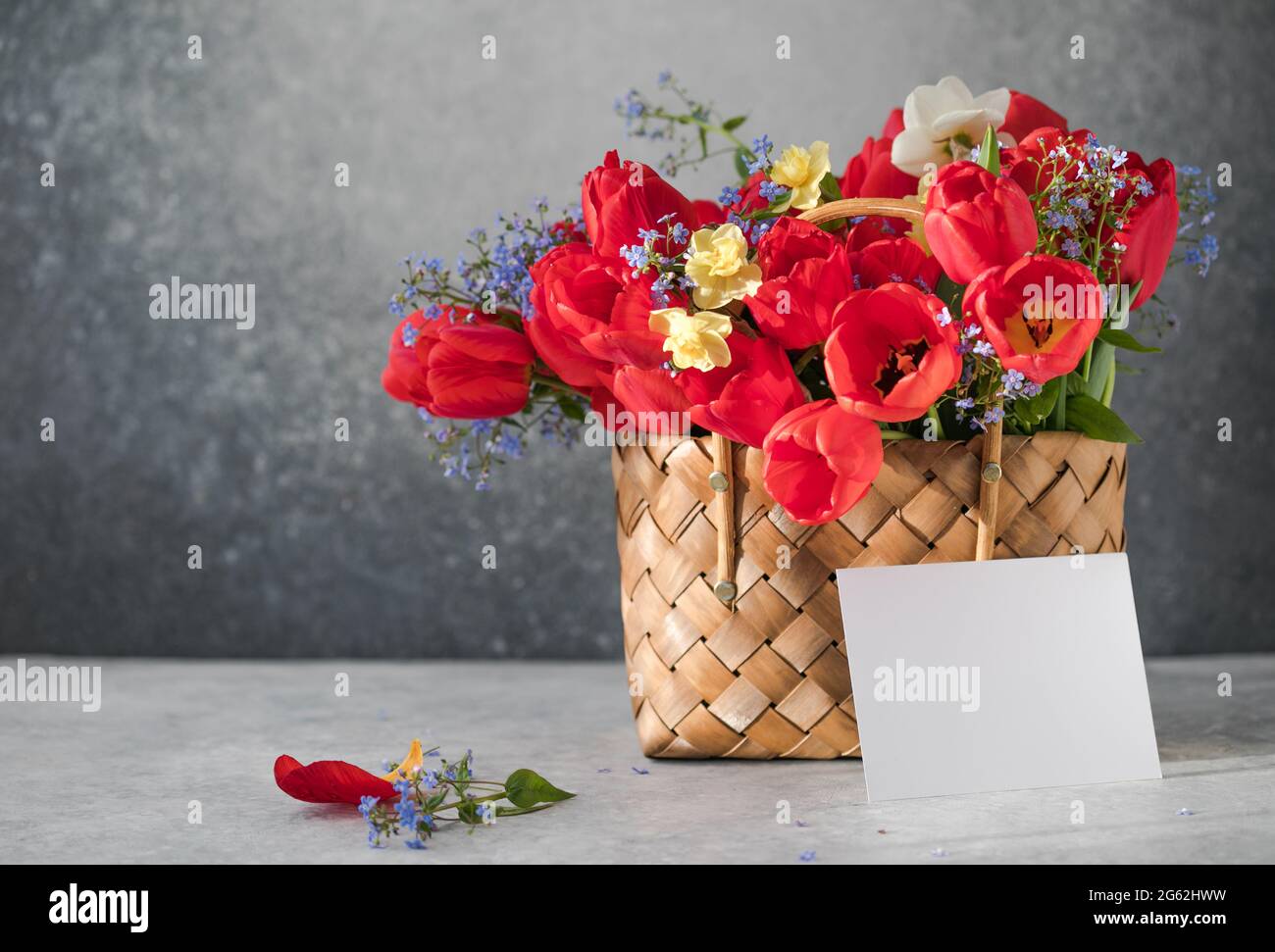 Summer or spring bouquet of daffodils and red tulips with blank in a ...