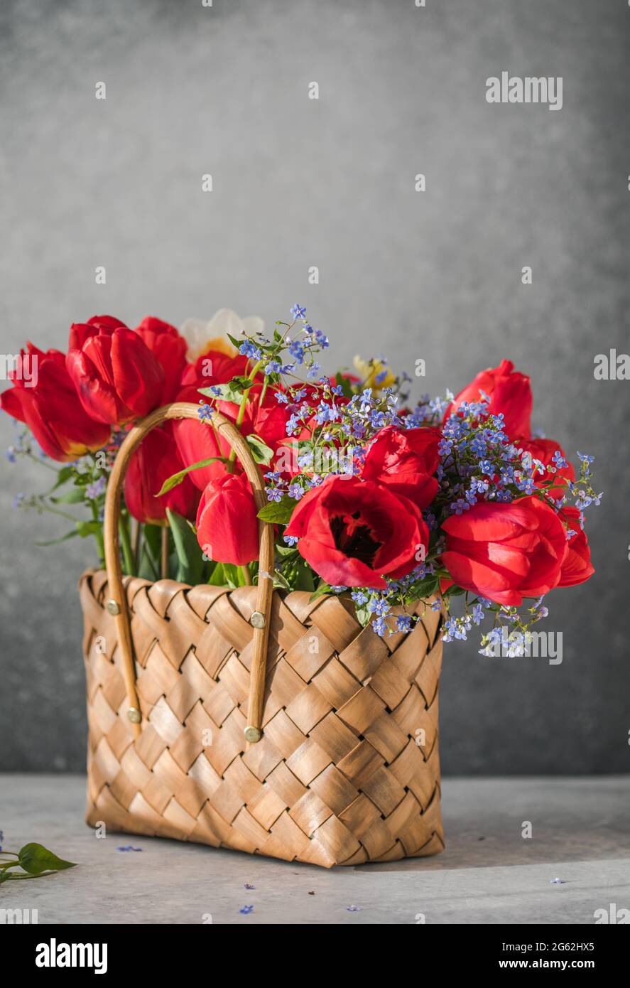 Summer or spring bouquet of daffodils and red tulips in a wicker basket ...