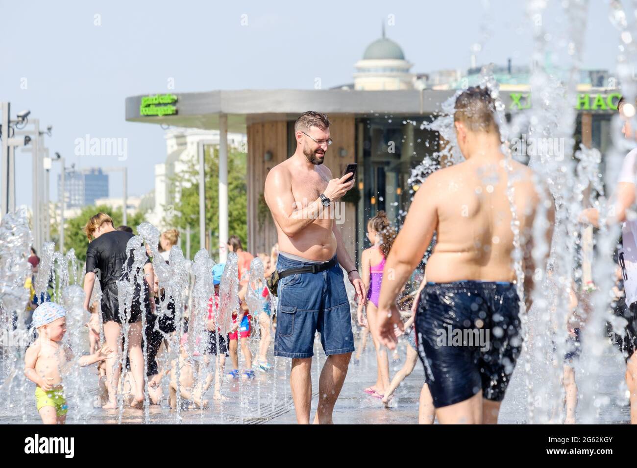 Moscow, Russia, June 26, 2021. Men and children bathe in the jets of the fountain in the Muzeon Park. Water entertainment for the townspeople on a hot summer day. Stock Photo