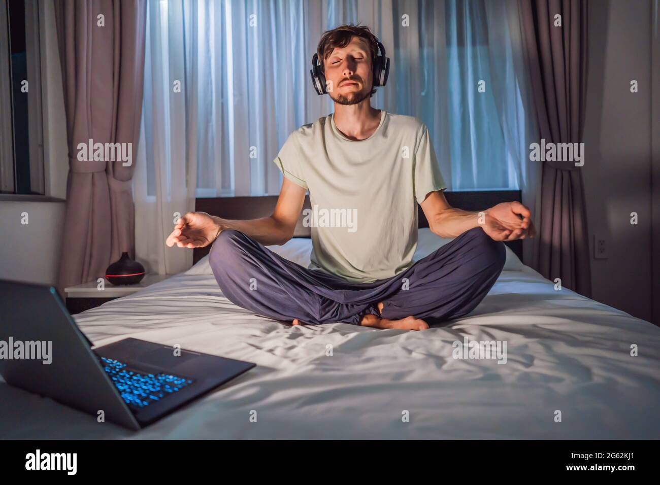 Man meditates on bed using meditation app. sport, technology and healthy lifestyle concept Stock Photo