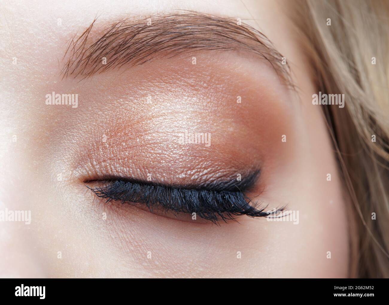Closeup macro shot of closed human female eye. Woman with natural evening vogue face beauty makeup. Girl with long lashes and black eye arrow. Stock Photo