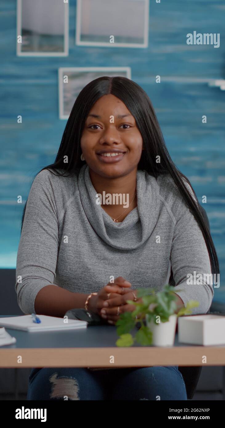Portrait of smiling student looking into camera while sitting at desk ...