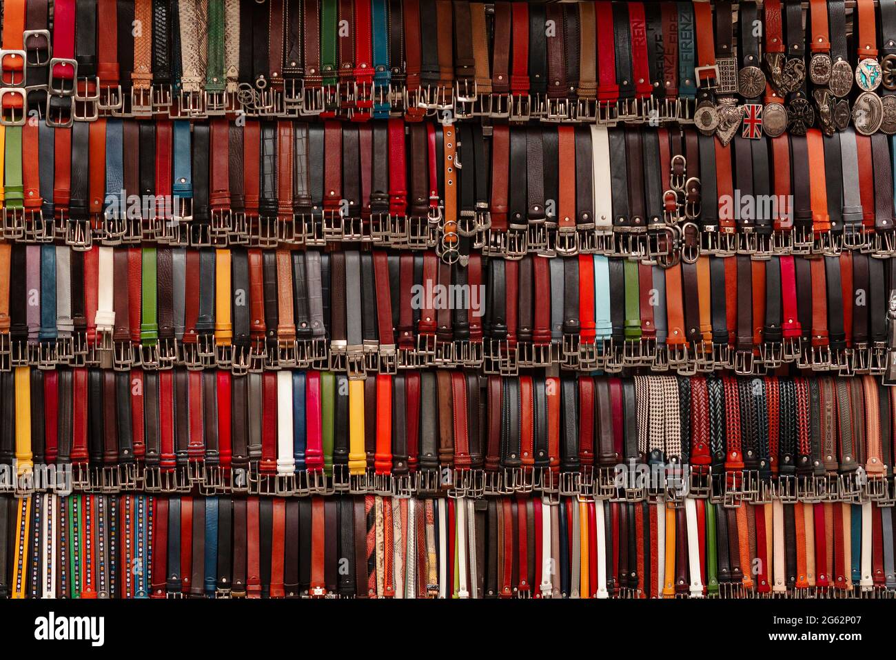 Many colored italian leather belts on display on a market. Fashion background. Stock Photo