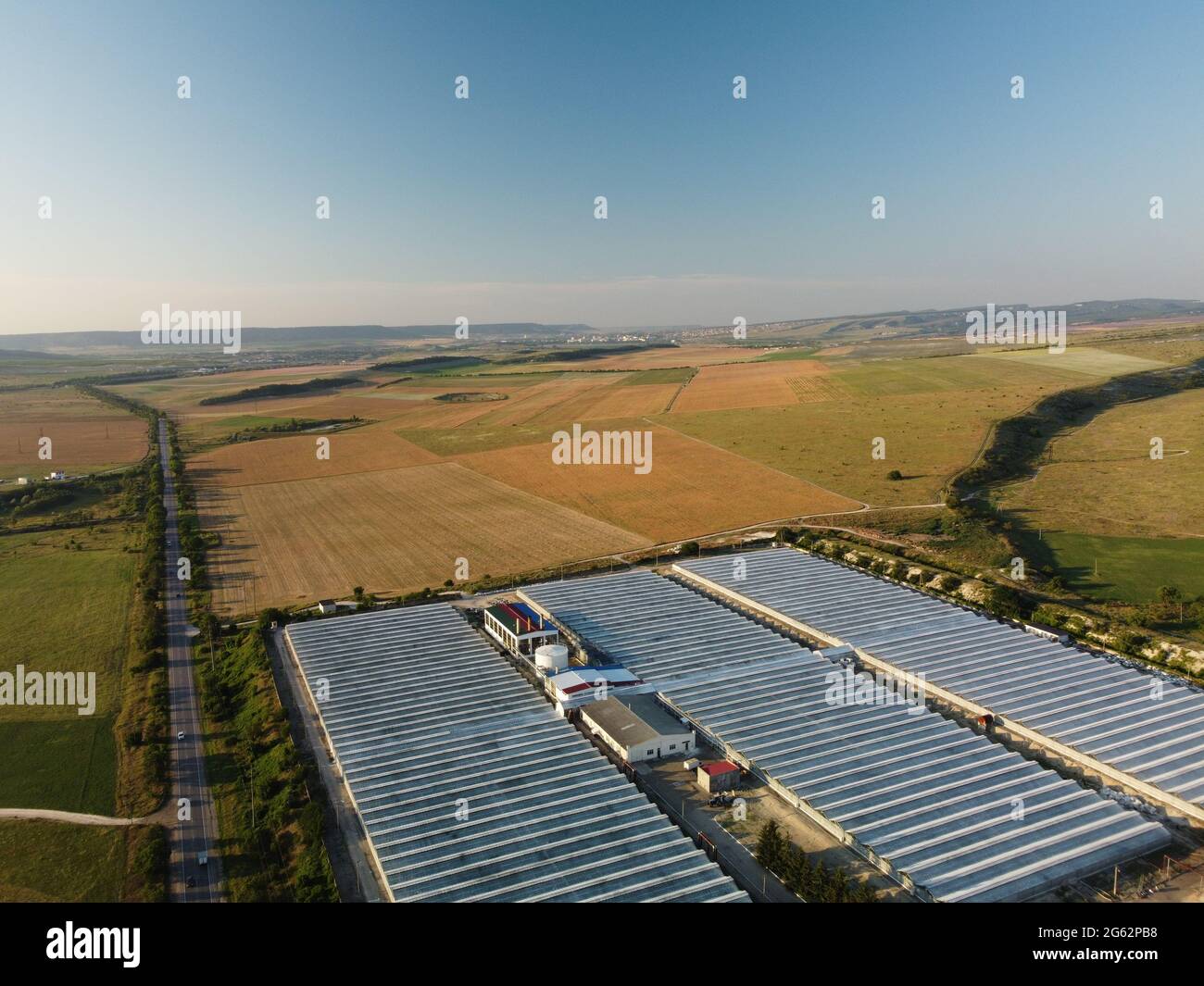 Aerial drone view of huge areas glass greenhouse for growing vegetables. Greenhouse farming, agriculture industry. Flying over large industrial Stock Photo