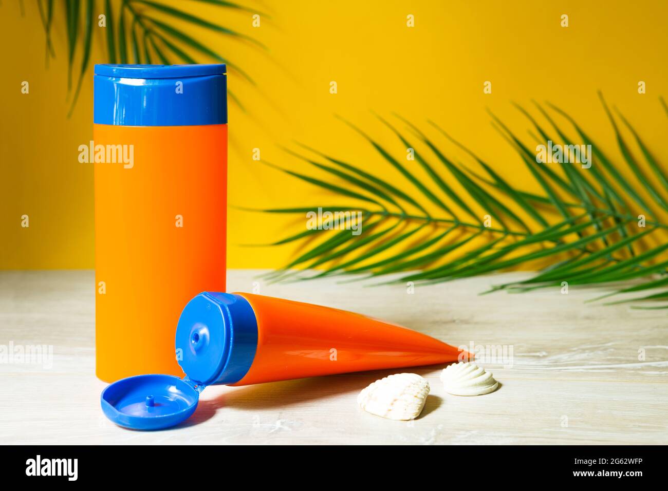 Tubes with mock up sunscreens on the table with yellow summer background. UV protection of the skin with an SPF filter, hair care-shampoo and conditio Stock Photo
