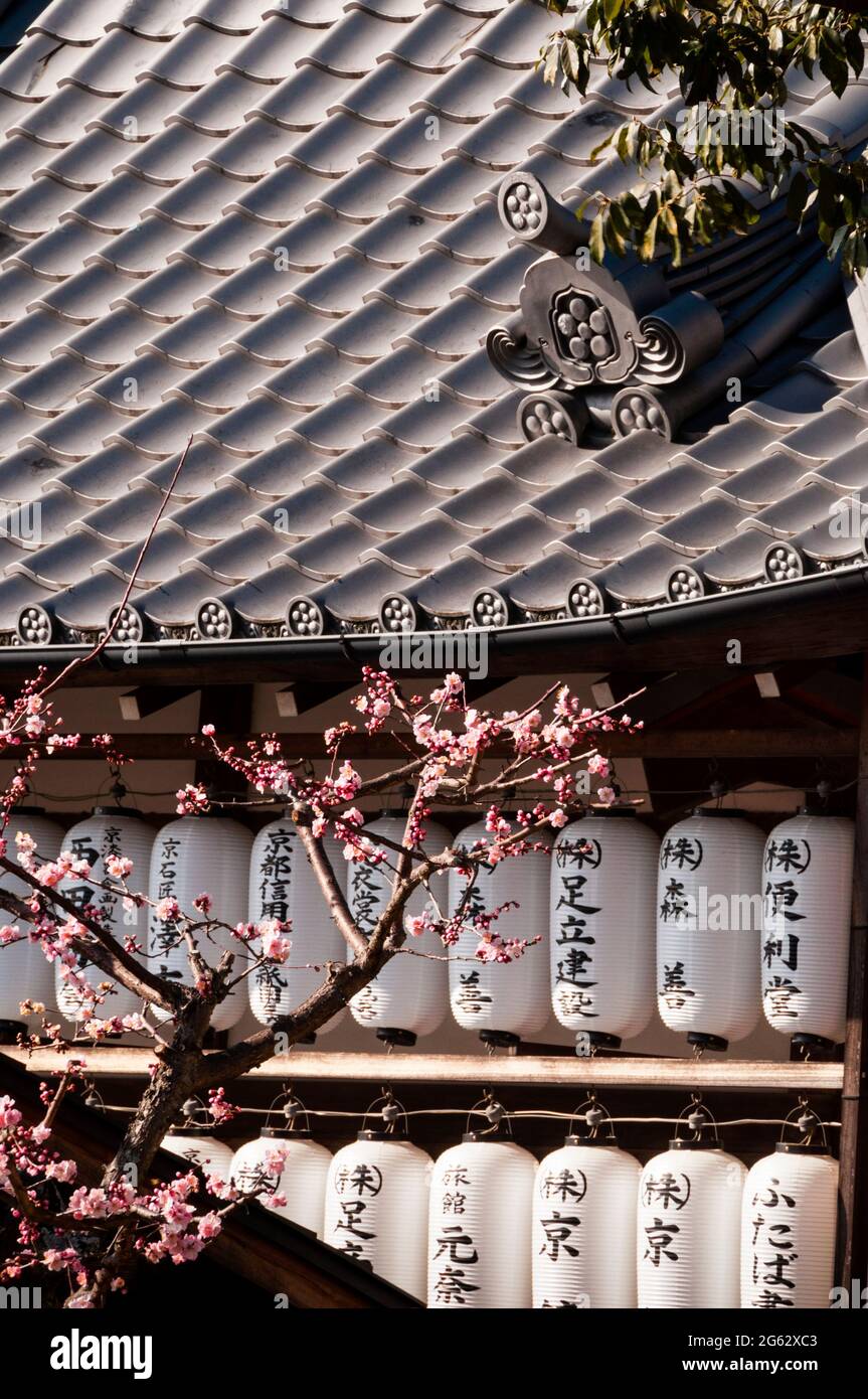 Kawara or grey ceramic roof tiles and silk paper lanterns of a Japanese temple in Kyoto, Japan. Stock Photo