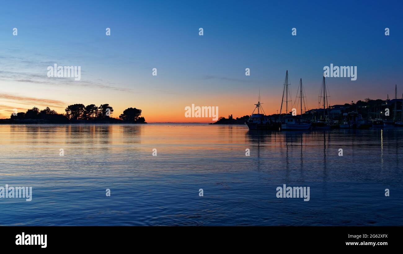 Fishing boats tied up to a jetty at sunrise in Riverton, Southland, south island, New Zealand. Stock Photo