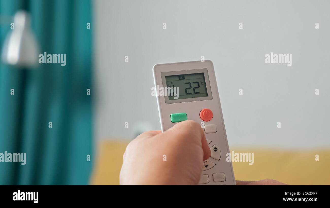 Close-up of a hand regulating an air conditioner with a remote control. Stock Photo