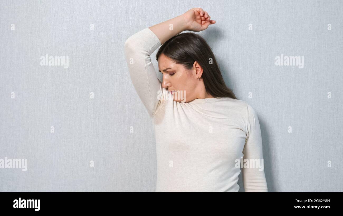 young woman with a sweat problem under armpits. The concept smells bad