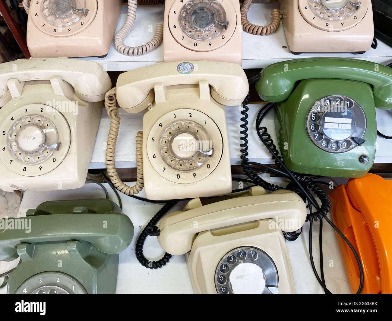 From above composition of old fashioned rotary telephones placed on white wooden shelves Stock Photo