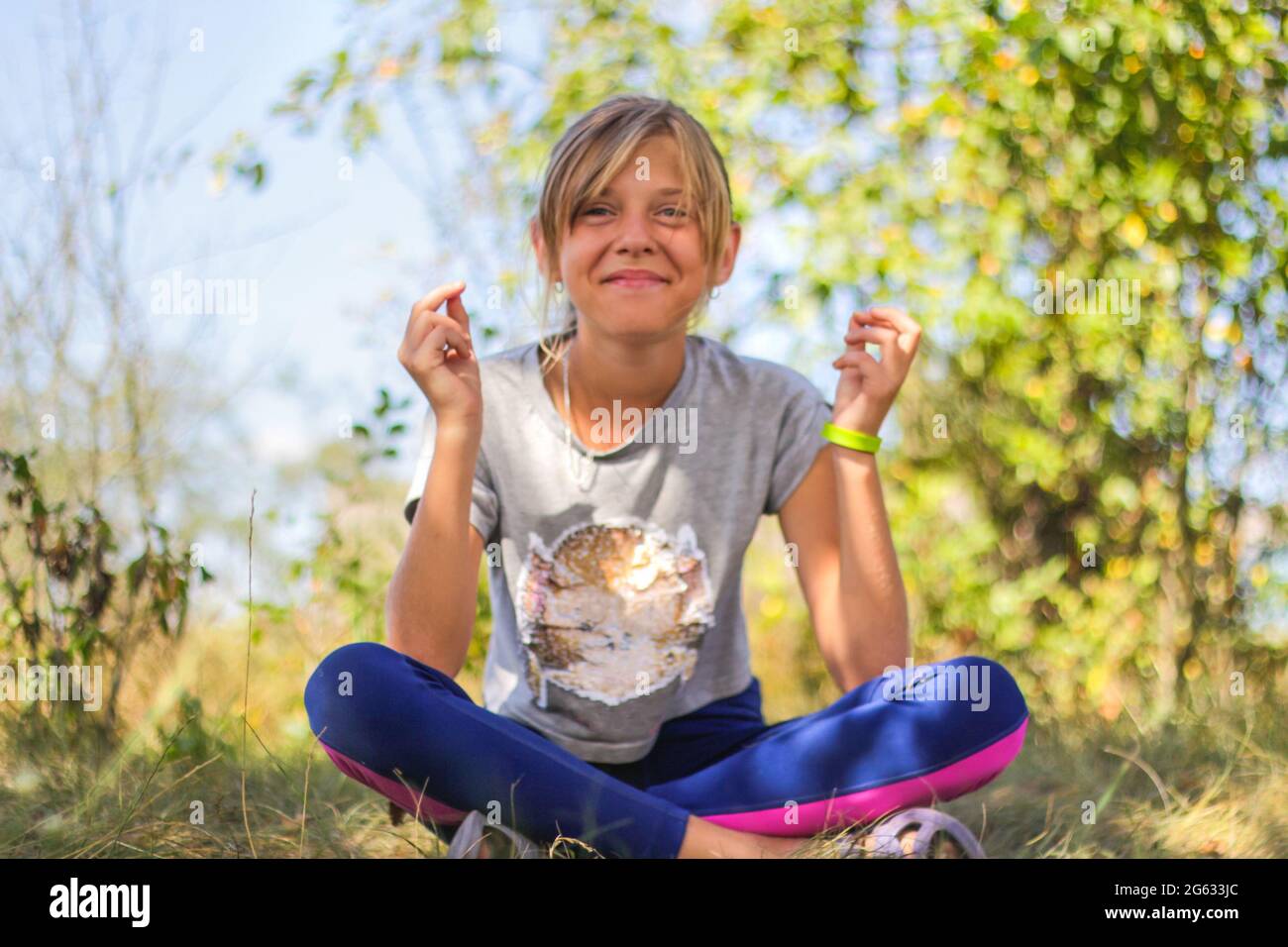Defocus caucasian preteen girl practicing yoga in park, forest, outdoor, outside. Meditation, concentration, mantra. Wellness lifestyle. Portrait of s Stock Photo