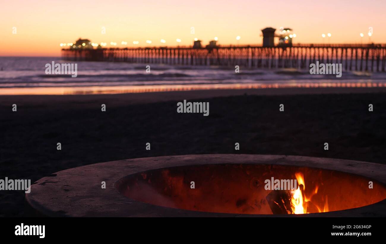 Campfire pit by Oceanside pier, California USA. Camp fire burning on ocean beach, bonfire flame