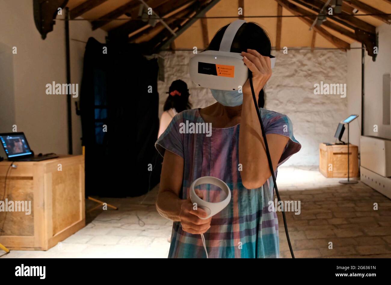 A visitor watches 3D content through virtual reality VR goggles as she experience an interactive artwork entitled 'Inside Out' which deals with social behavior at the opening of the Jerusalem Design Week the city’s annual celebration of creativity at Hansen House on July 01, 2021 in Jerusalem, Israel. This year’s festival of local and international creativity revolves around the theme of a “Runaway Circus” about the pandemic and running away from the days of virtual life toward nature, alternative culture and identities. Stock Photo