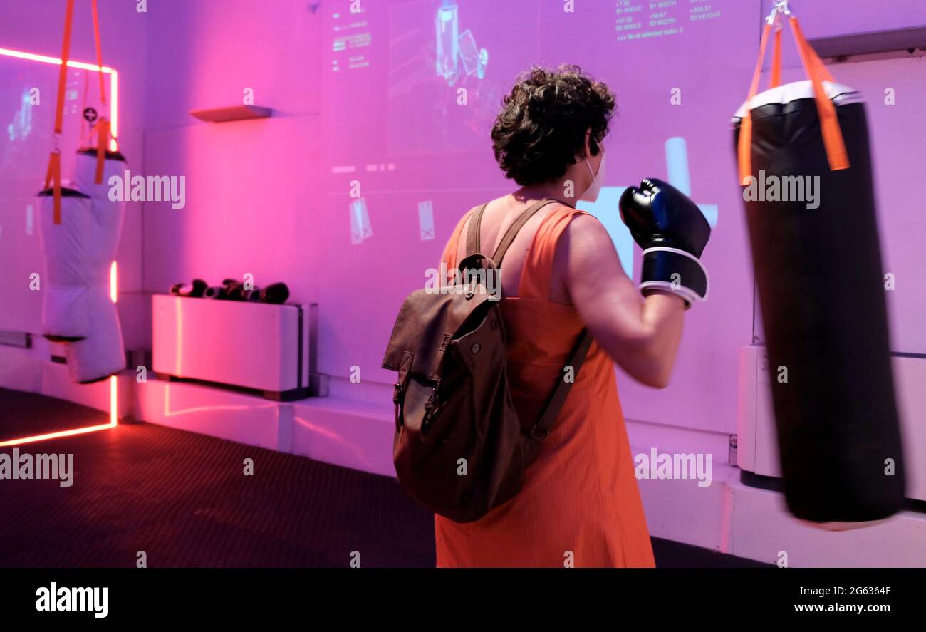 A visitor hits a punching bag as she takes part in an active punching role through an interactive artwork entitled "Punch. Generate. Freak" at the opening of the Jerusalem Design Week the city’s annual celebration of creativity at Hansen House on July 01, 2021 in Jerusalem, Israel. This year’s festival of local and international creativity revolves around the theme of a “Runaway Circus” about the pandemic and running away from the days of virtual life toward nature, alternative culture and identities. Stock Photo