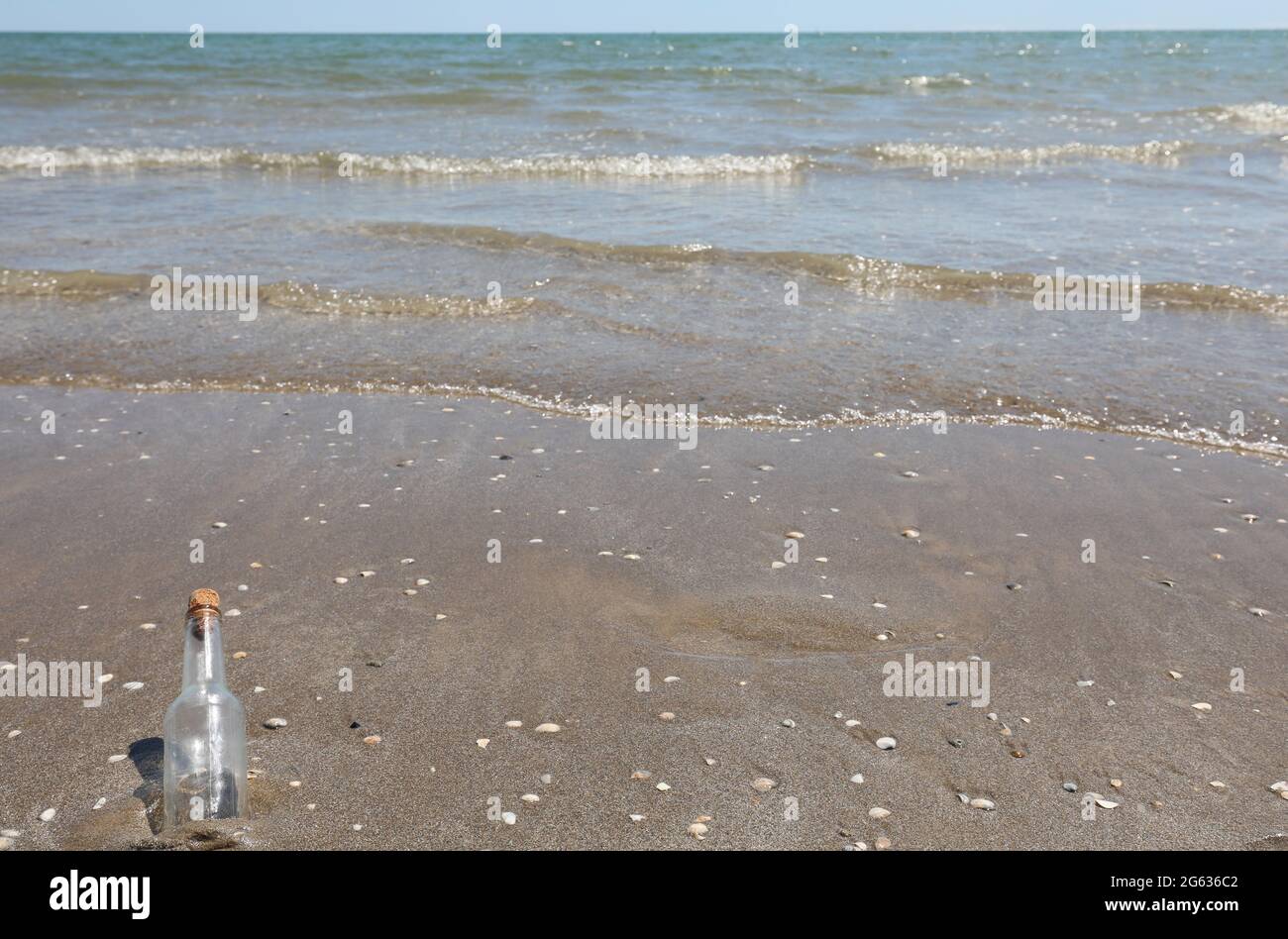 glass bottle stranded on the shore near the beach that can contain a treasure map Stock Photo