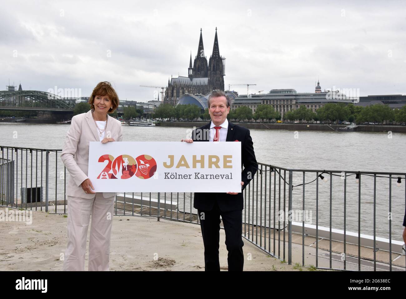 Cologne, Germany. 01st July, 2021. Henriette Reker, Mayor of the City of Cologne, and Christoph Kuckelkorn, President of the Cologne Carnival Festival Committee, l-r, pose with a poster in front of Cologne Cathedral at the press conference for the 2023 anniversary of the Cologne Carnival. The city and the festival committees have big plans for this from the start of the session in November 2022 Credit: Horst Galuschka/dpa/Alamy Live News Stock Photo