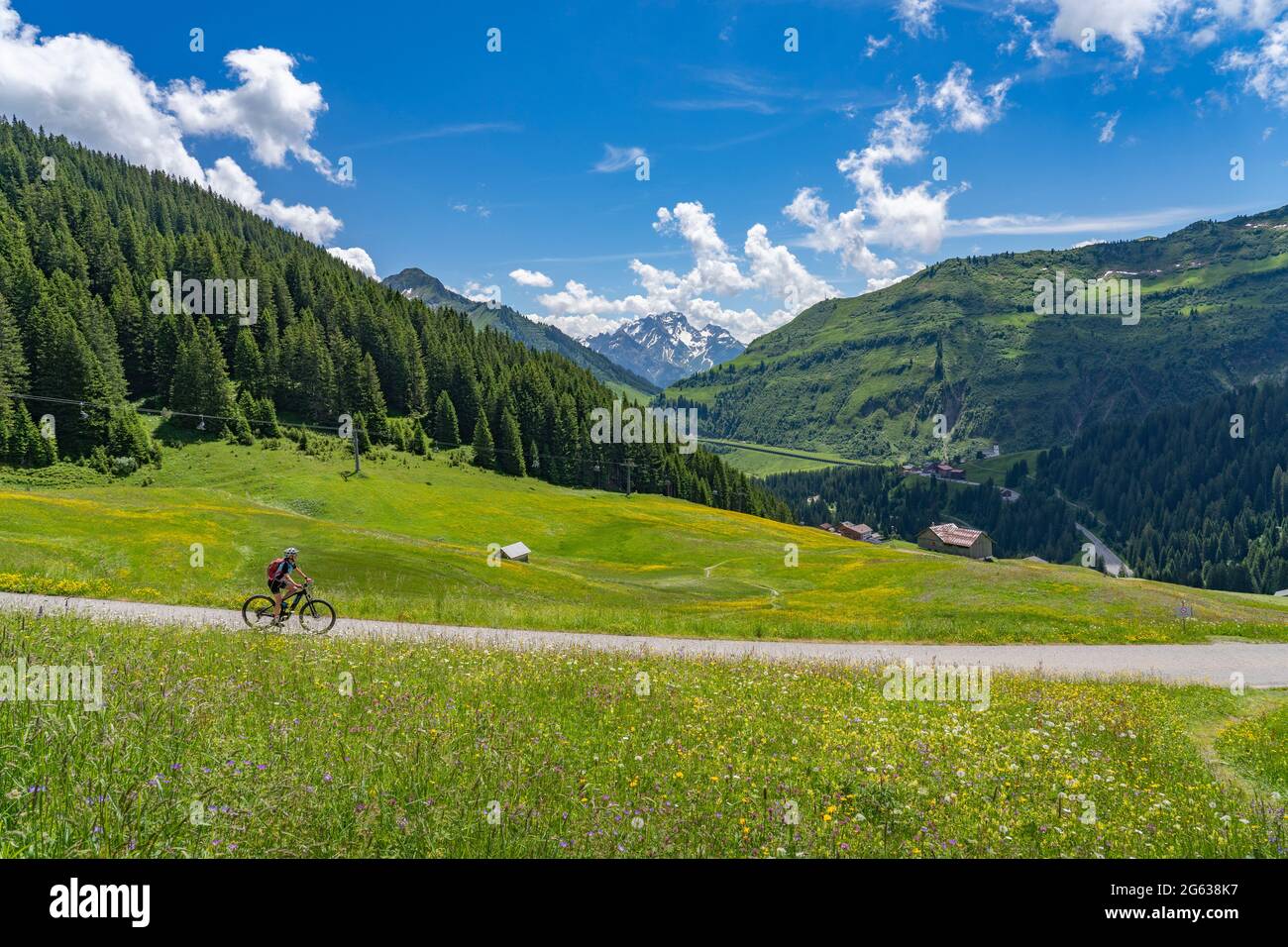 happy senior woman riding her electric mountain bike near the famous mountain village of Damuels in Bregenz Forest mountain of Vorarlberg, Austria Stock Photo