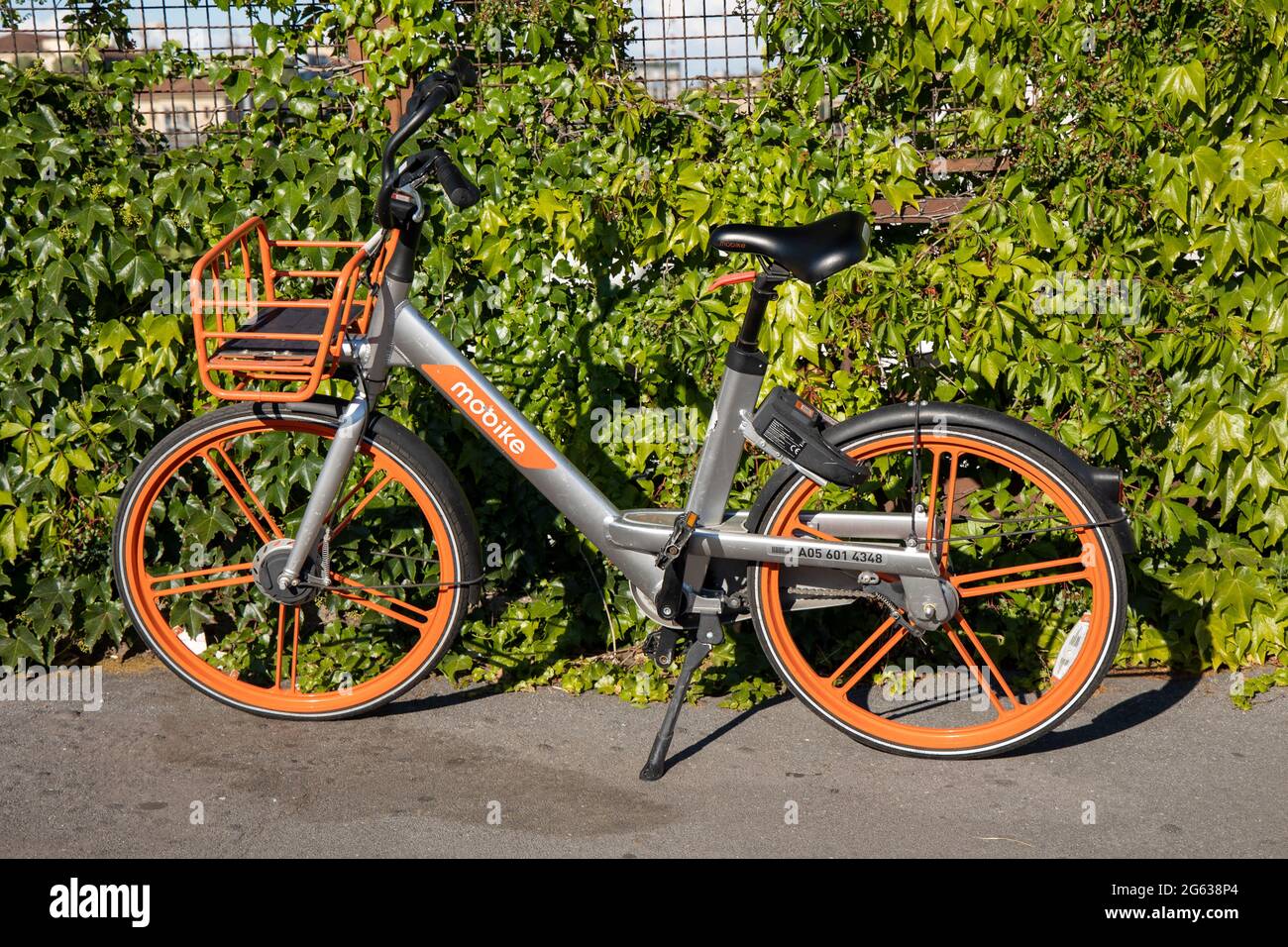 Milan, Italy, july 1 2021 -  Bicycle rental service Mobike .Orange bicycles with basket for traveling around Milan waiting cyclists. Public street tra Stock Photo