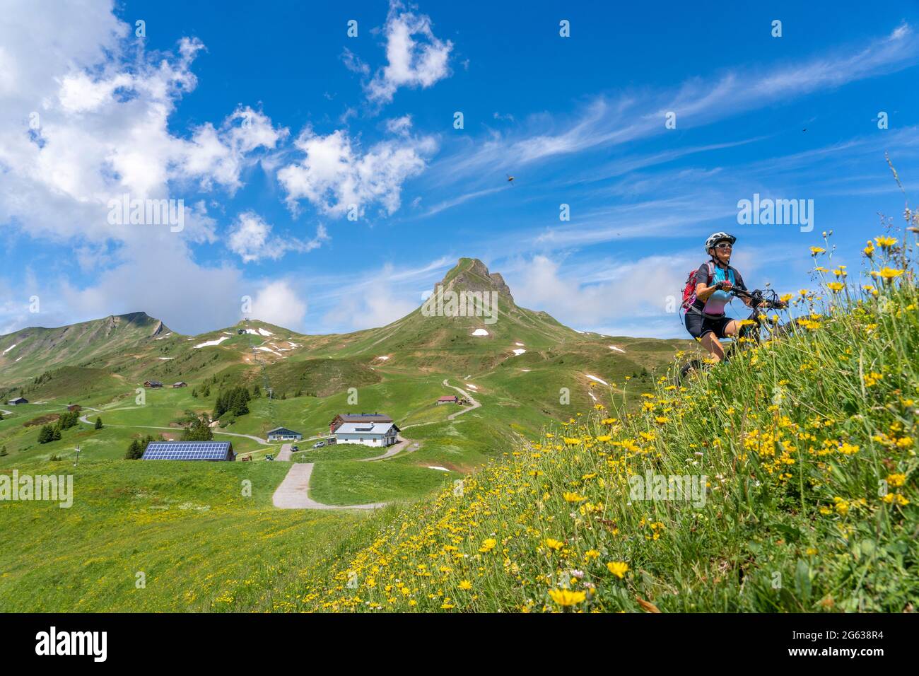 happy senior woman riding her electric mountain below Mittagsspitze summit near the village of Damuels in the Bregenz Forest mountain of Vorarlberg, A Stock Photo