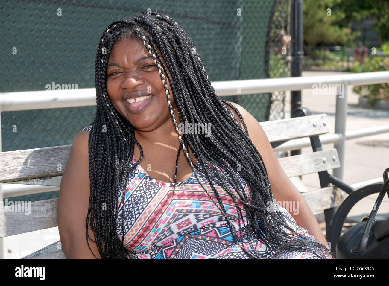 Posed portrait of a cheerful laughing attractive Nigerian American woman with long hair extensions. In Brighton Beach, Brooklyn, New York City. Stock Photo