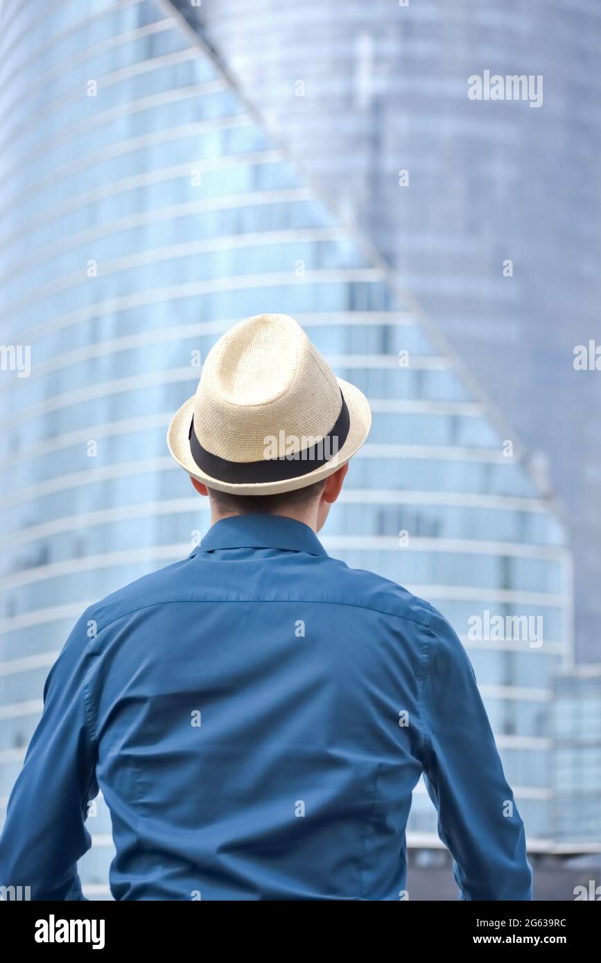 Rear view of a standing man who thinks and looks at blurred office ...