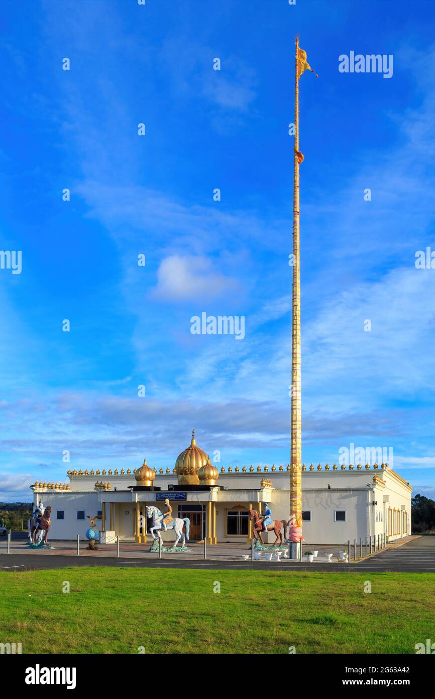 A Sikh temple with a giant flagpole outside flying the Nishan Sahib, the Sikh flag. Gurudwara Kalgidhar Sahib, Tauranga, New Zealand Stock Photo