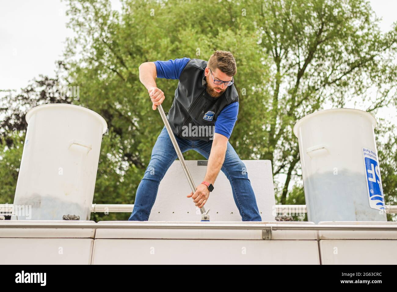 Lower Saxony, Germany. July 2 2021: Matthias Letmeyer stands on a fish transporter and uses a landing net to distribute young set eels into two large buckets. The Lower Saxony Anglers' Association releases young eels and helps them avoid obstacles on their natural migration route. The eel was once an important cultivated and bread fish in northern Germany. But hydroelectric power plants and weirs block the way for young eels from the North Sea to the rivers and streams. Photo: Mohssen Assanimoghaddam/dpa Credit: dpa picture alliance/Alamy Live News Stock Photo