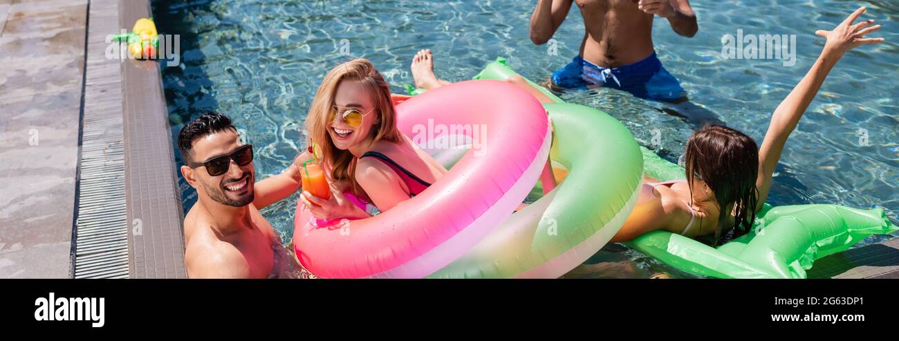 joyful multiethnic friends relaxing in swimming pool together, banner ...