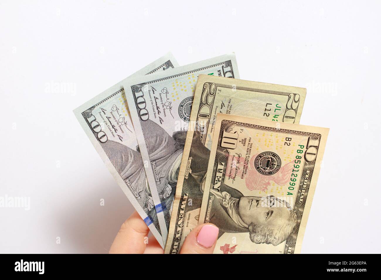 A woman's hand holds many dollar bills on a white. Credit, corruption, borrowing money and financial literacy Stock Photo