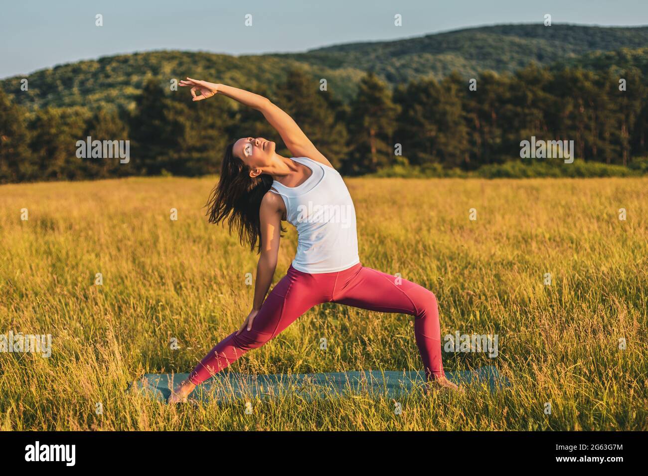 Female Doing Yoga Poses On Sunny Morning In The Green Garden Stock