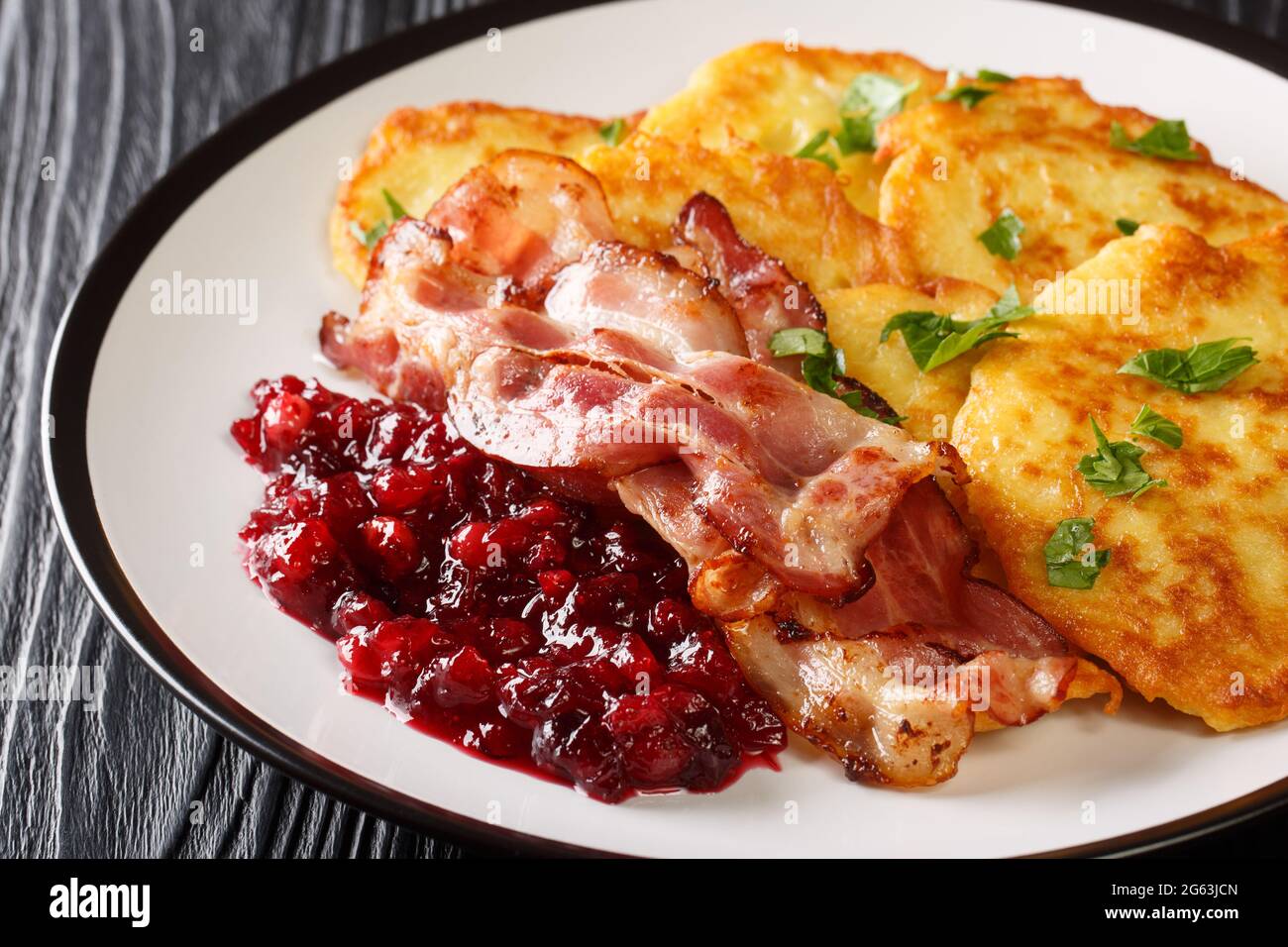 Swedish potato pancakes with fried pork raggmunk med flask close-up in a plate on the table. horizontal Stock Photo