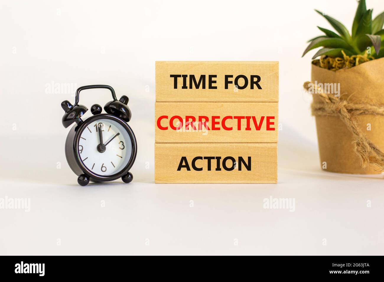 Time for corrective action symbol. Blocks with words time for corrective action. Black alarm clock, house plant. Beautiful white background. Copy spac Stock Photo