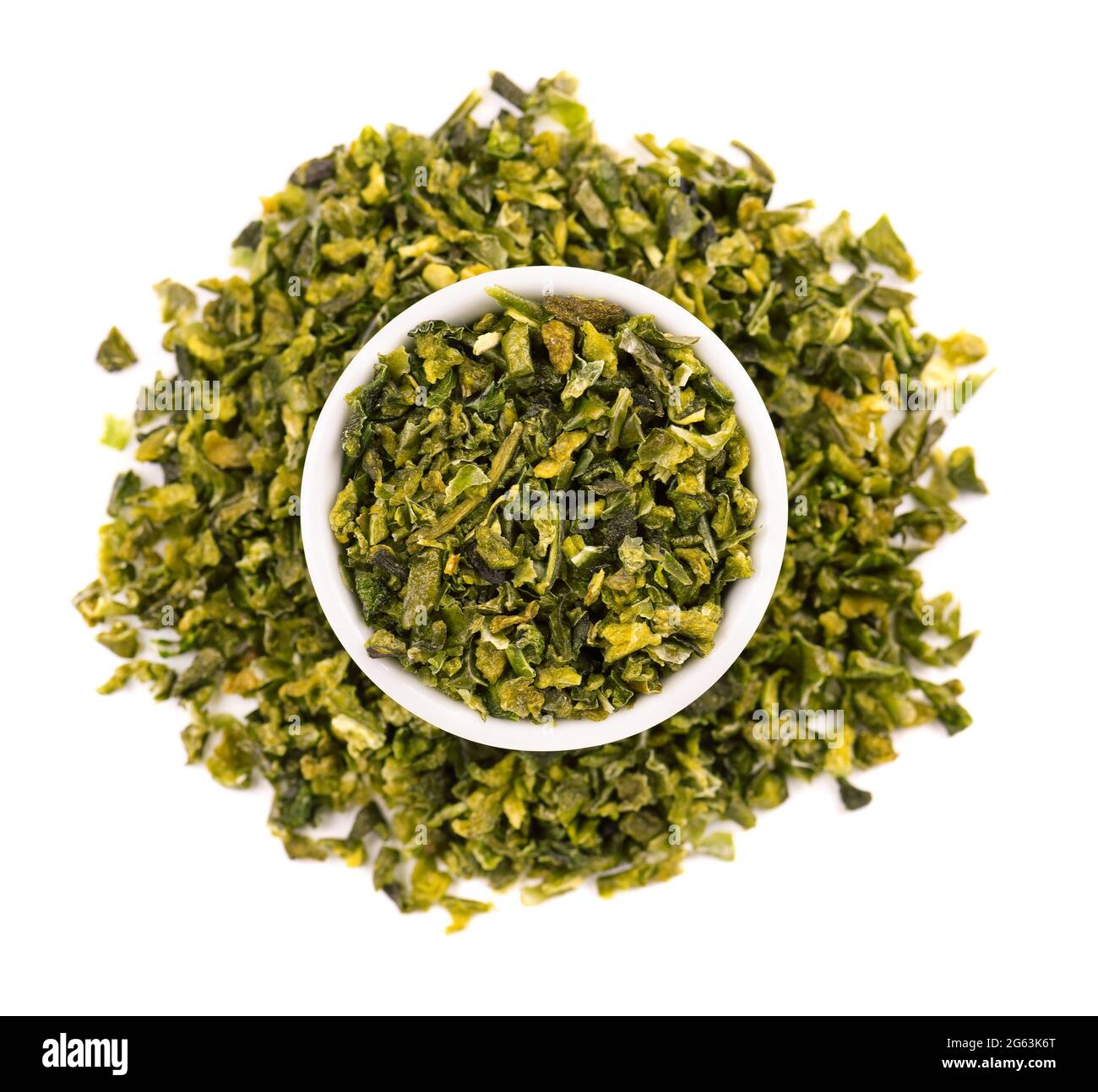 Dried green paprika flakes with seeds in bowl, isolated on white