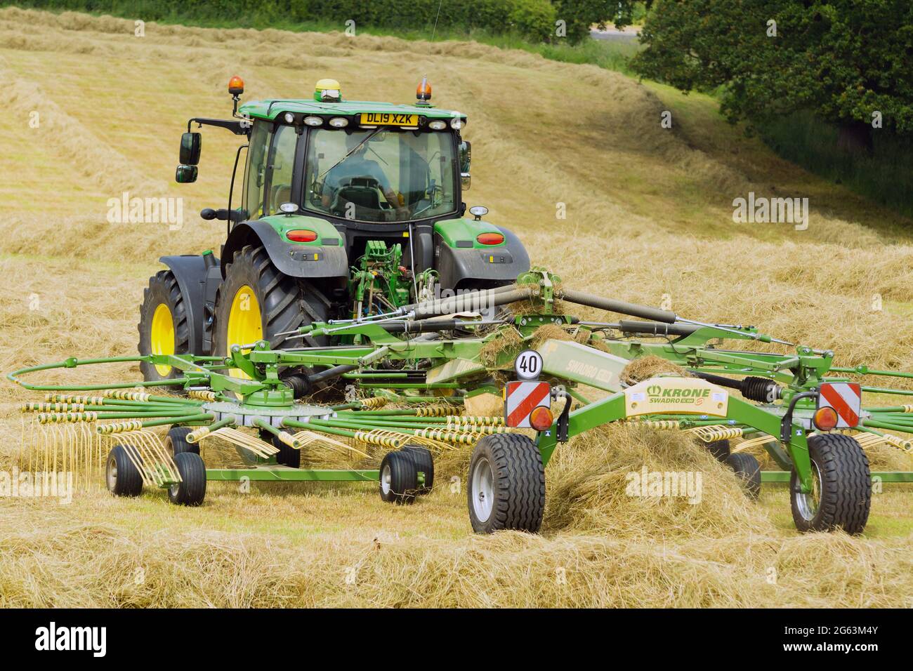 John Deere tractor working in a field with a twin rotor hay turner or