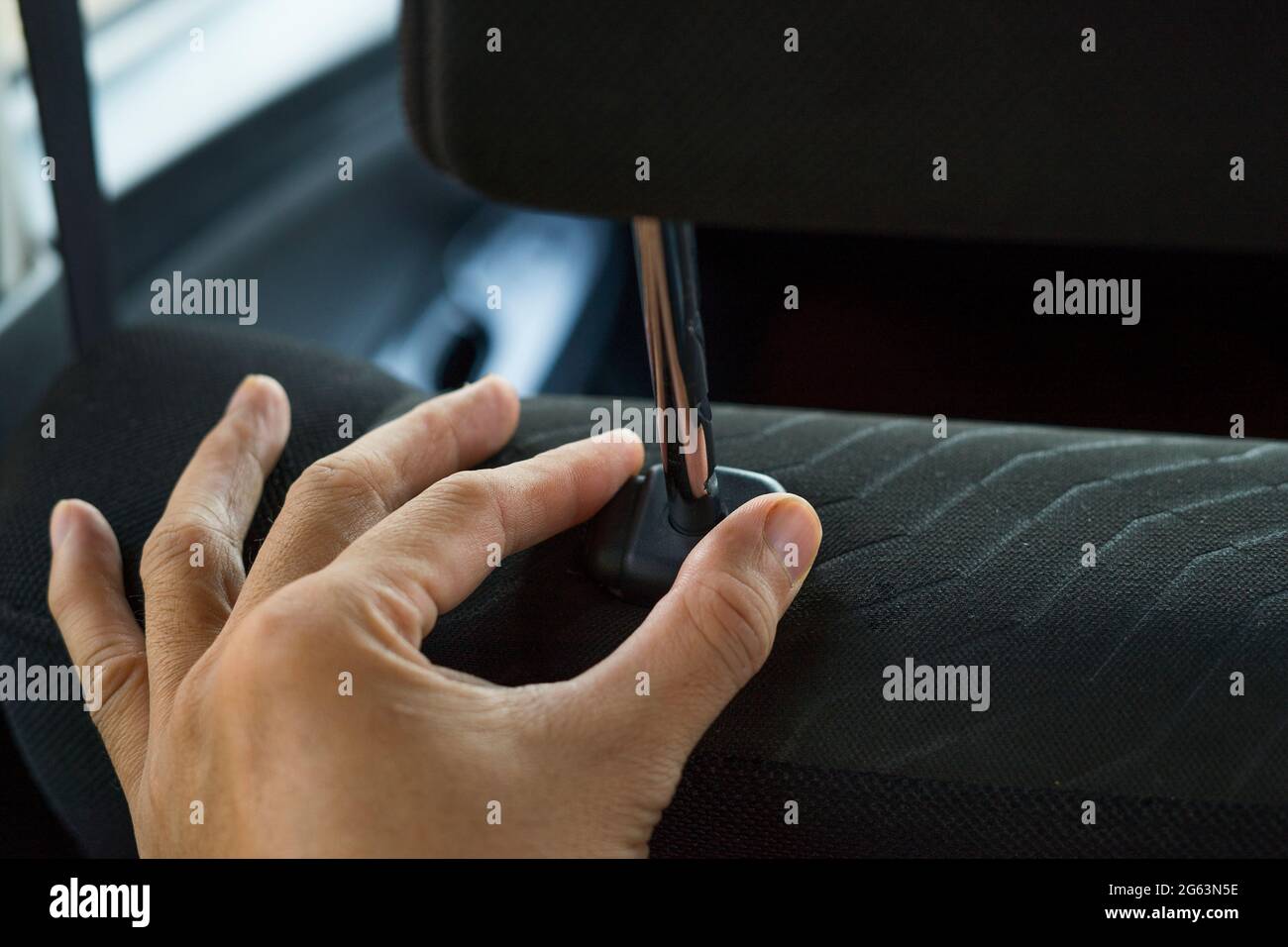 Hand adjusts headrest in car interior. adjusting the seat position in