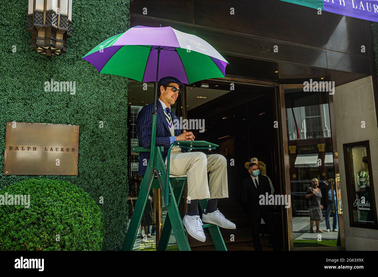 NEW BOND STREET PALACE LONDON 2 July 2021. A staff member dressed as an  umpire outfit sits outside the Ralph Lauren store in New Bond Street  decorated for the 2021 Wimbledon tennis