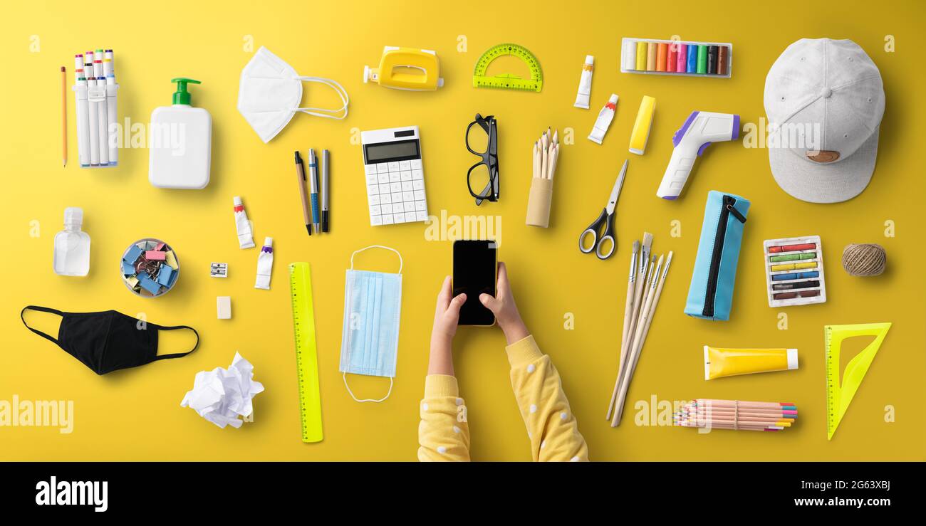 Flat lay top view of child, face mask and school supplies, back to ...