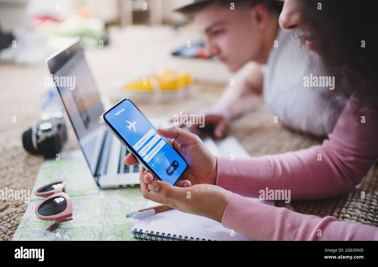 Unrecognizable couple with smartphone planning holiday, booking flight. Stock Photo