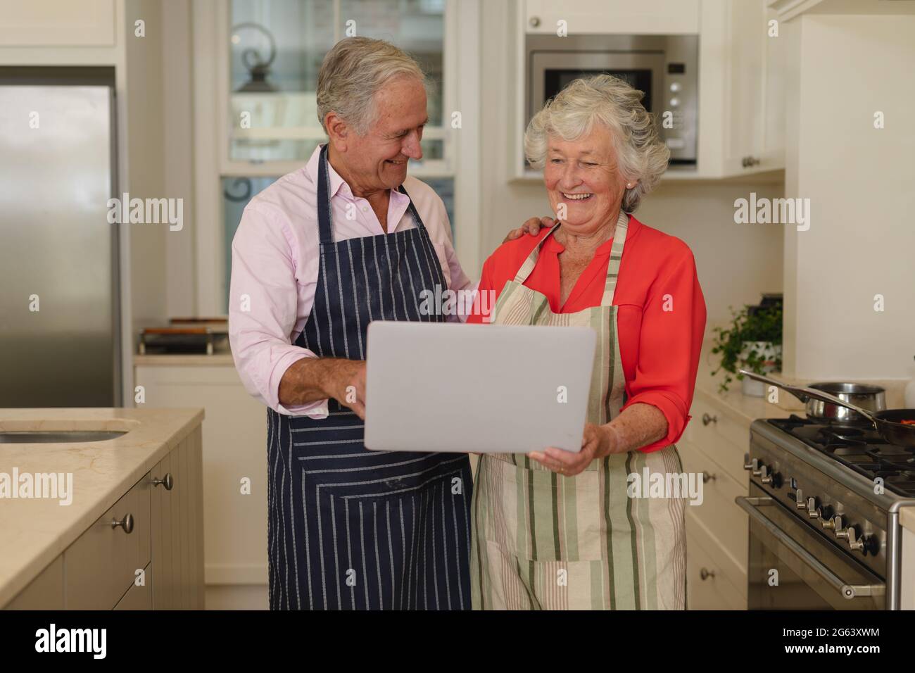 Senior caucasian couple using laptop together in kitchen Stock Photo