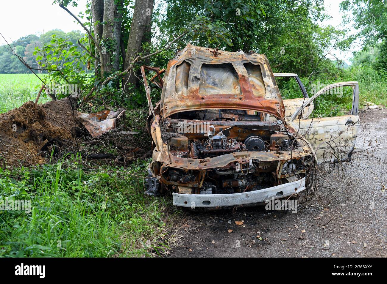 A burned-out car dumped on a roadside pull in area in a countryside road lay-by. Picture taken Ryedown lane near Romsey Hampshire England. Stock Photo