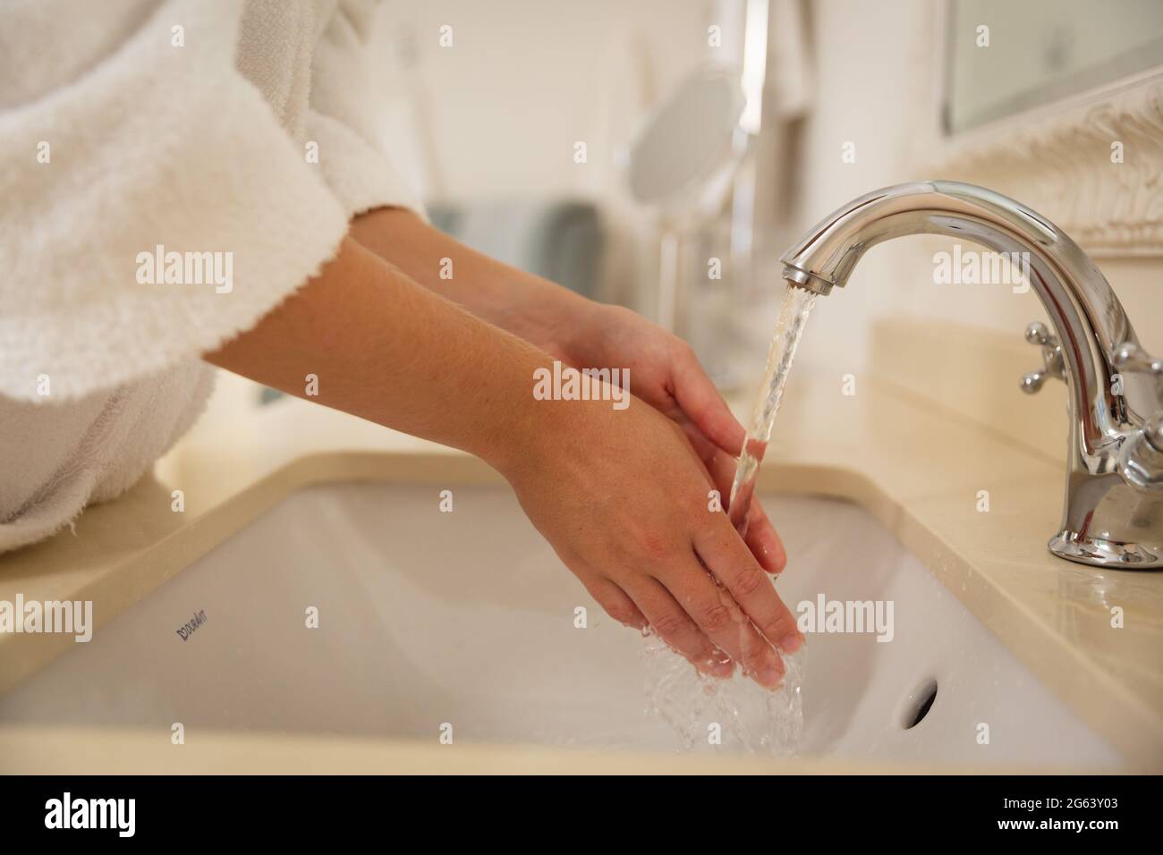 Midsection of caucasian woman in bathroom wearing bathrobe washing hands in basin Stock Photo